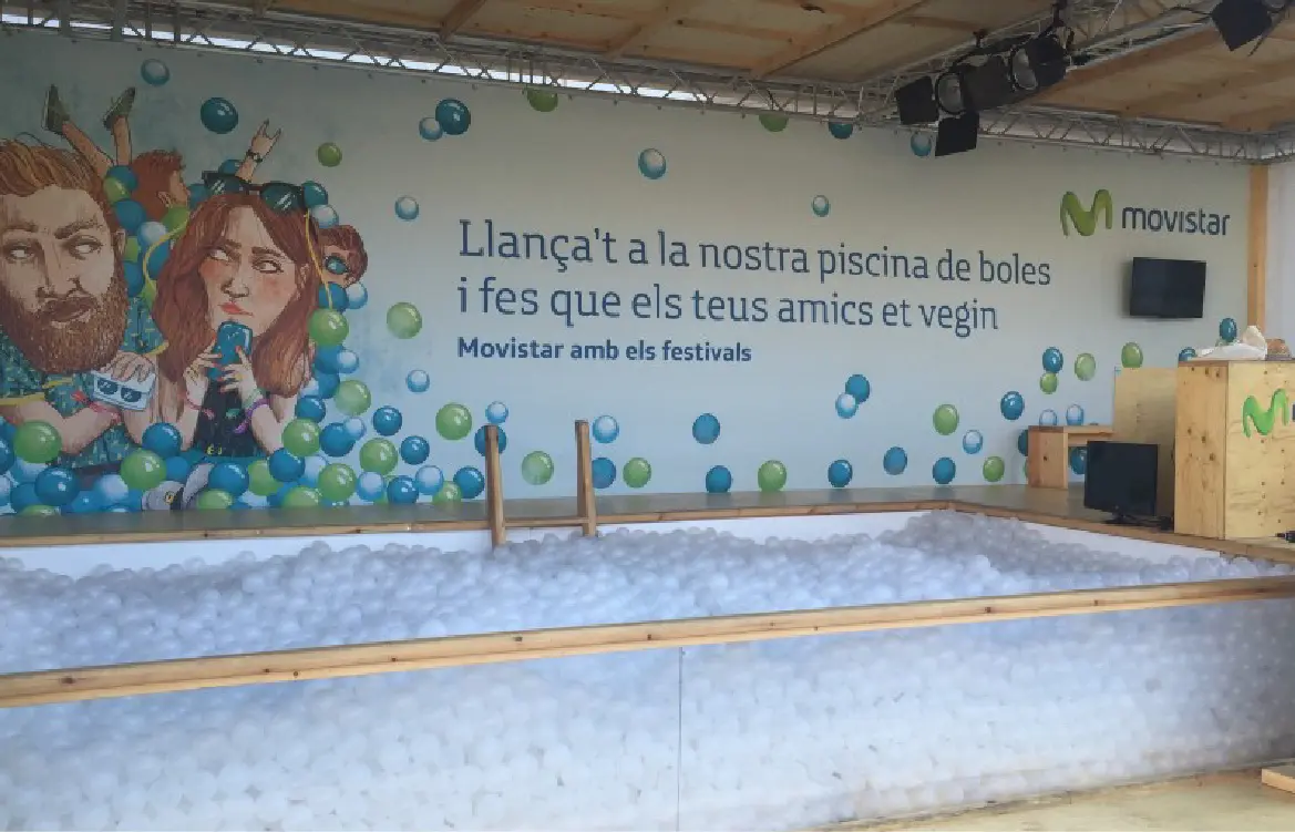 Movistar ball pit at a festival, with a mural and a pool full of white balls