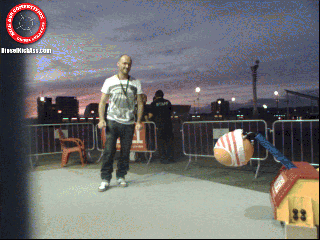 Man standing in front of the kicking cabinet at dusk, with a red Kick Ass Competition badge in the corner