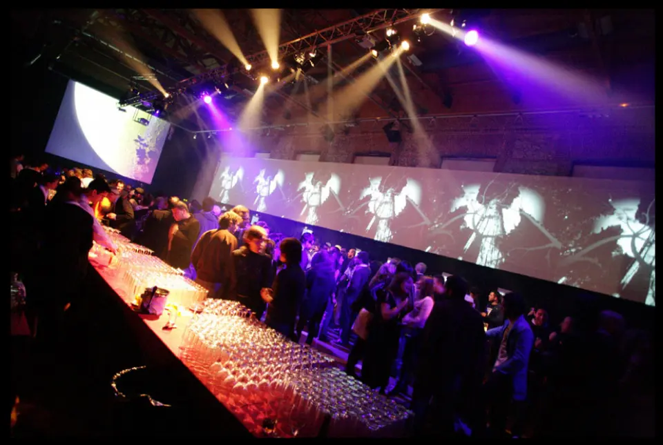 Party venue with a long bar and illuminated screens showing flowers along the wall