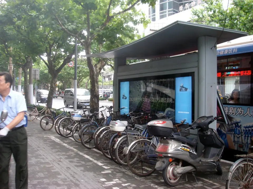 Man walking past the Nike interactive bus shelter with bicycles and scooters parked in front