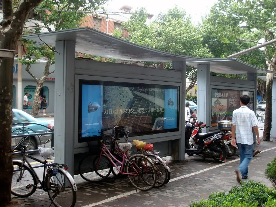 Man walking beside two Nike bus shelters on a Shanghai sidewalk