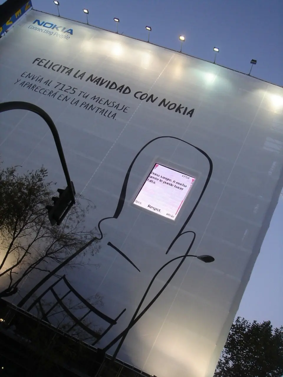 Large building banner with a lit screen mounted on it at dusk
