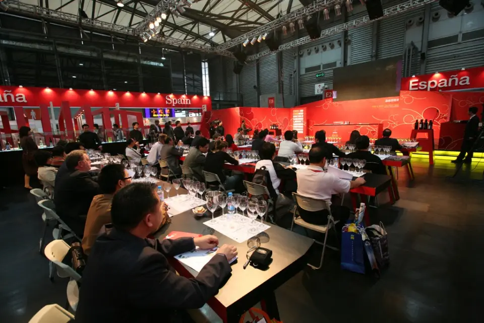 Guests seated at long black tables during a tasting in the red showroom