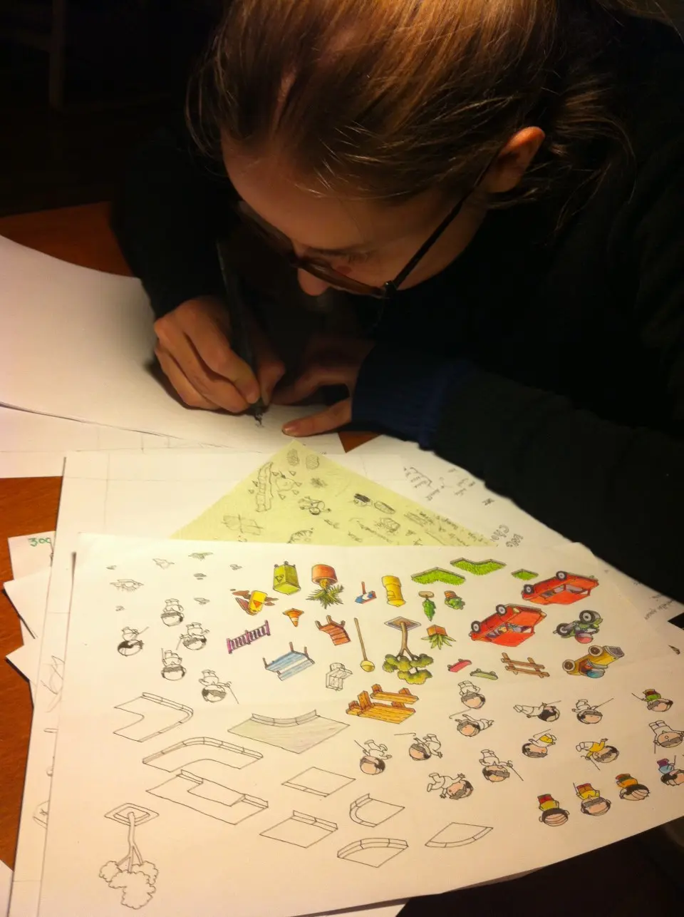 Illustrator drawing game objects on paper at a desk