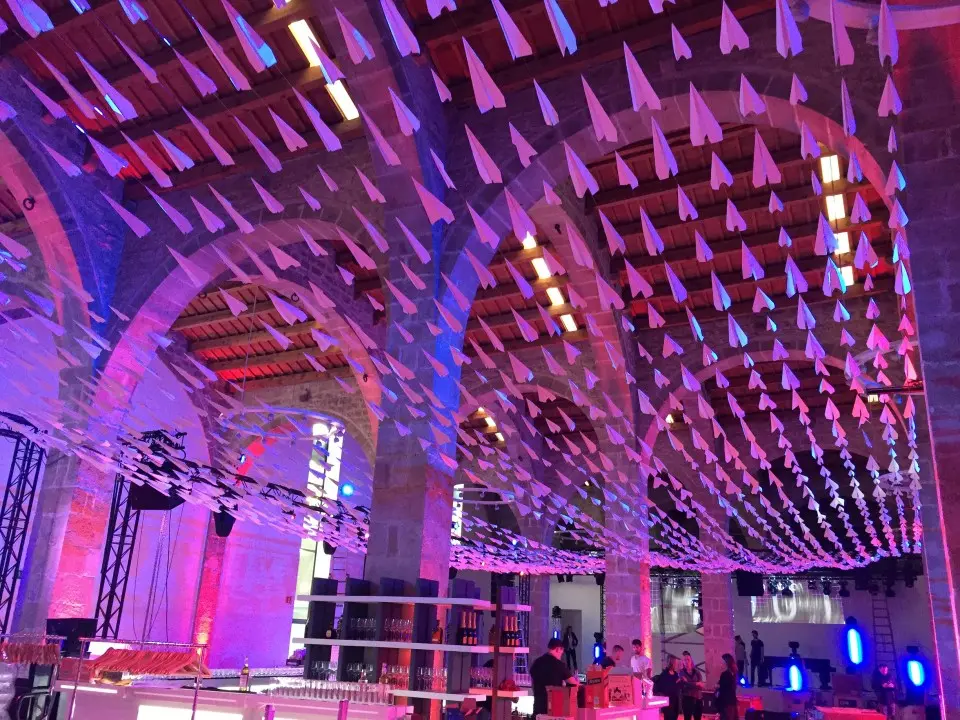 Thousands of paper planes hanging from the vaulted ceiling of the Museu Marítim, lit in purple and blue